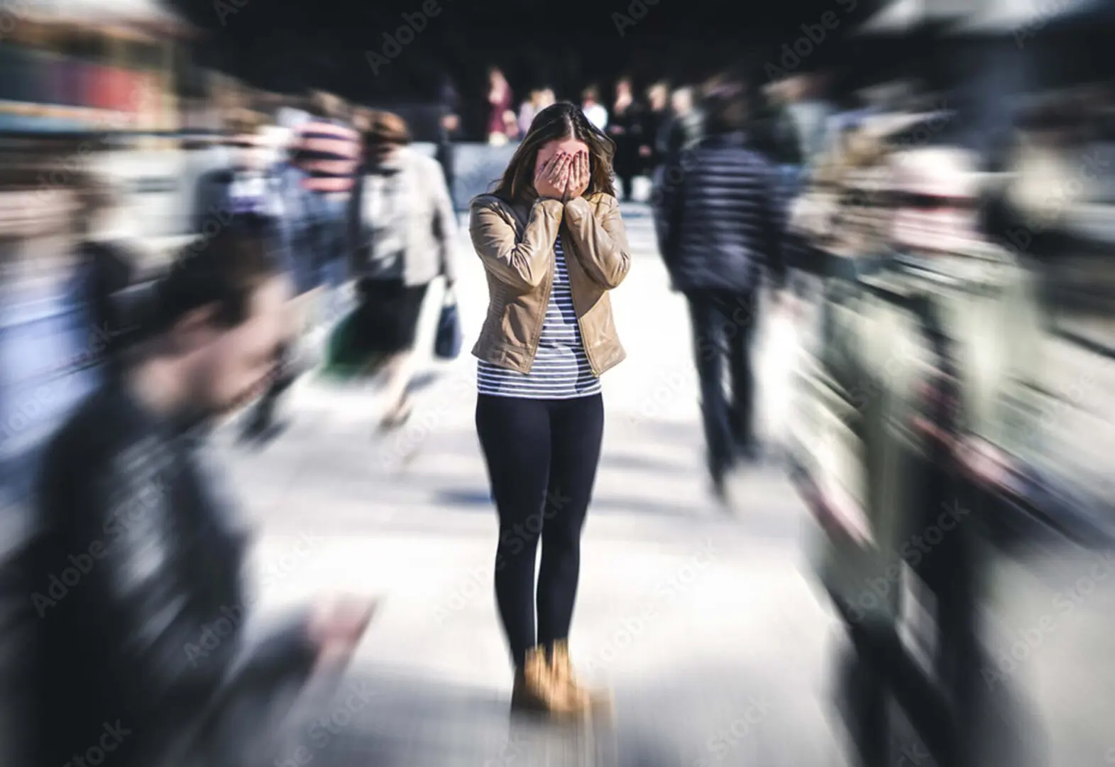 Amidst the bustling crowd, a person stands still with hands covering their face, creating a blurred motion effect around them—an island of calm that embodies the restorative essence of bioenergy healing.