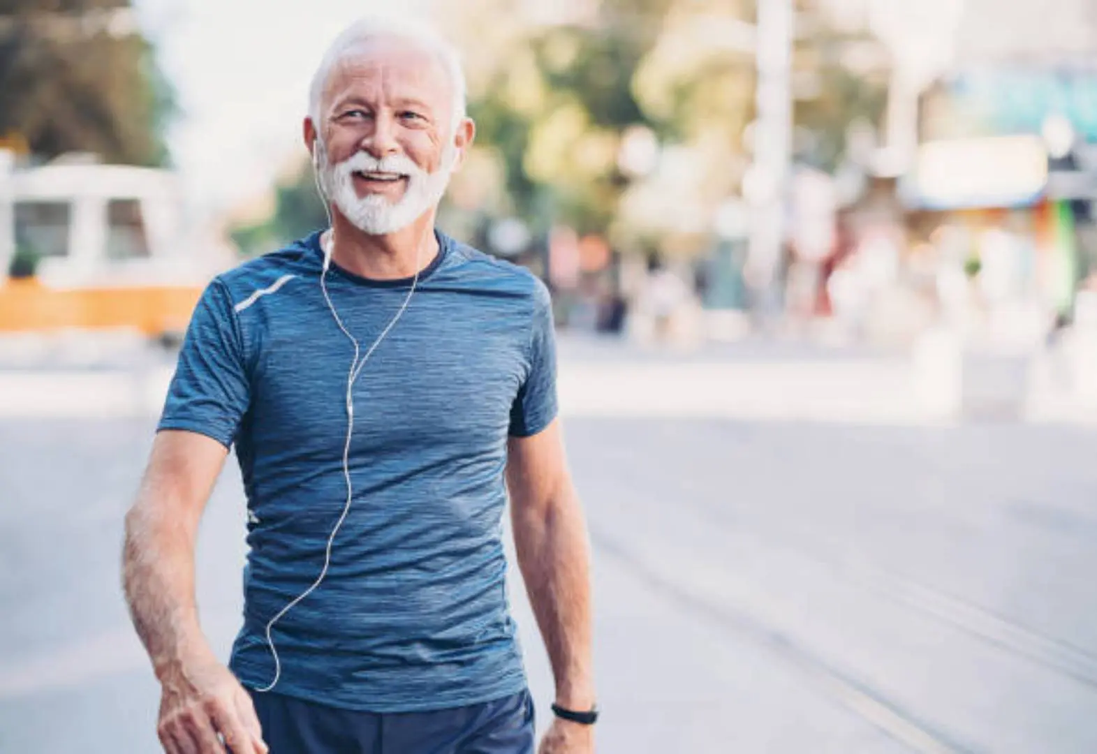 A man with headphones on walking down the street.
