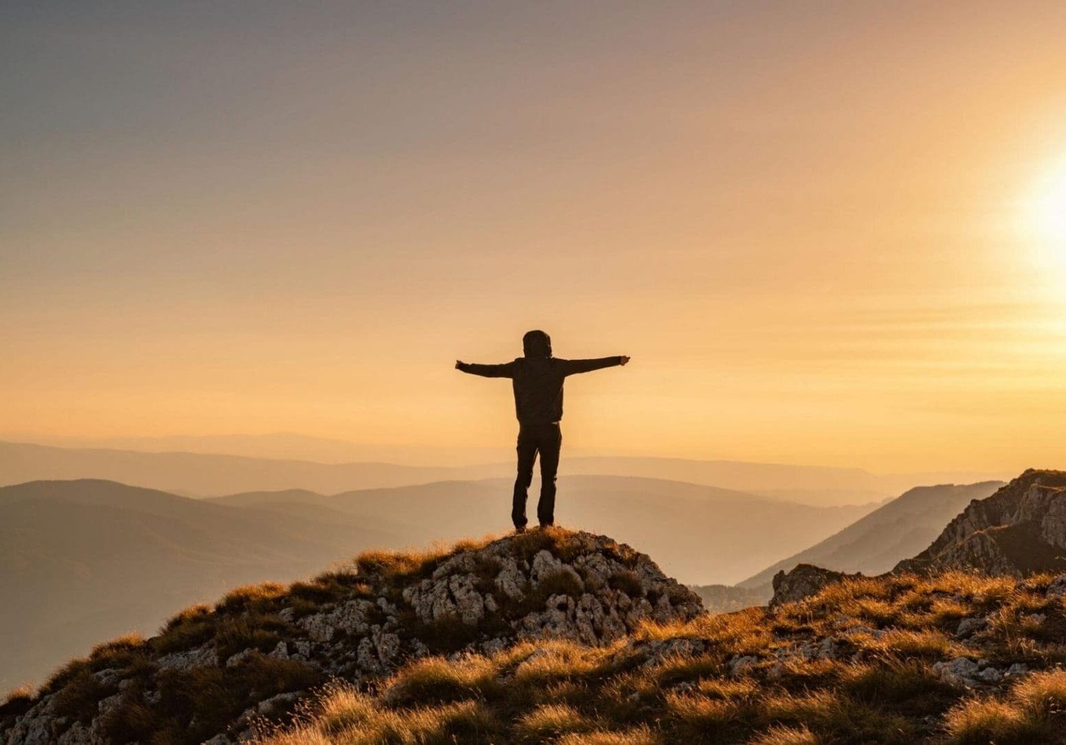 Man atop mountains dawn arms outstretched